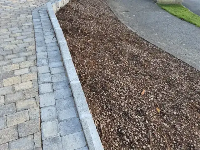 Gravel bed cleared of weeds beside a cobble-lock driveway