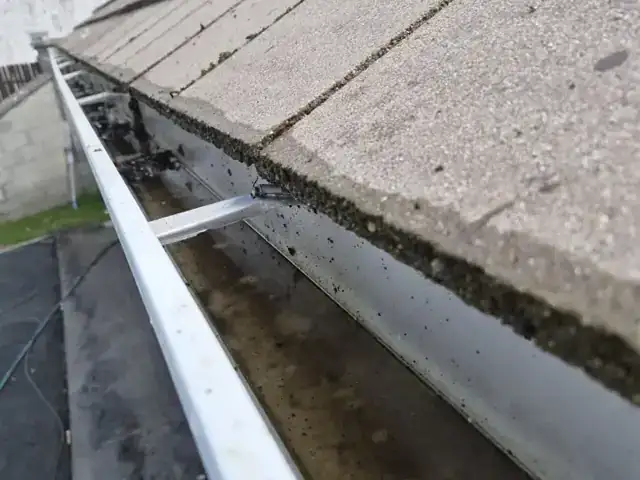 Close-up of a cleaned gutter under a tiled roof
